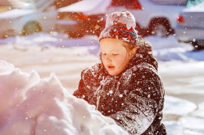 Girl wearing knit hat playing on snow outdoors