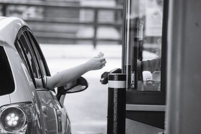 Cropped hand of woman giving credit card at drive through counter