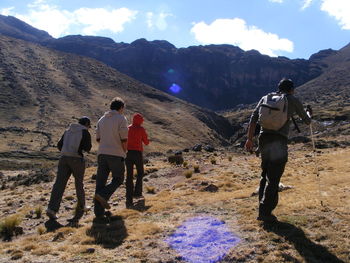 Rear view of men standing on mountain against sky