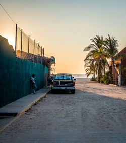 Car on street against clear sky at sunset