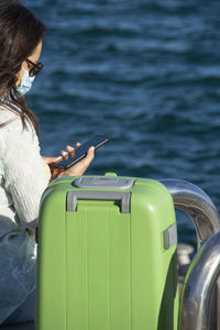 Rear view of woman using mobile phone while sitting in water