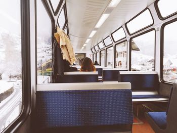 Rear view of woman sitting in train during winter