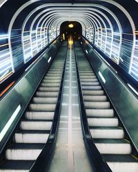 Low angle view of illuminated escalator in tunnel