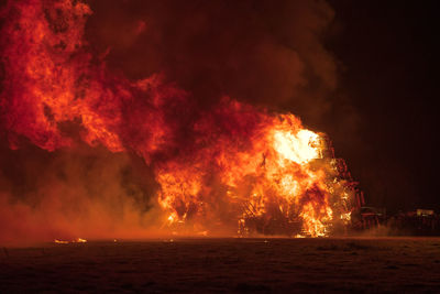 Bonfire display over land against sky at night