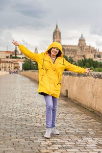 Full length of young woman standing against river