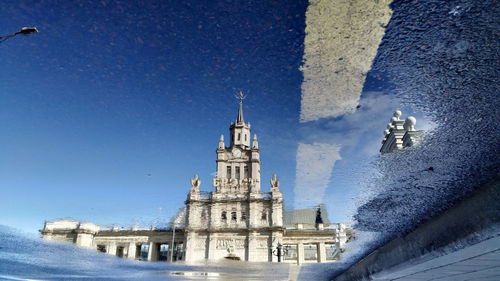 Reflection of historic building in puddle on street