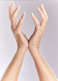 Cropped hands of woman with nail polish against white background