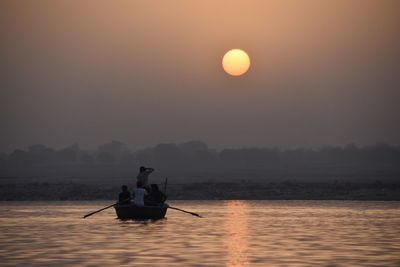 People rowing boat in sea against sky