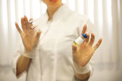 Midsection of scientist holding vial at laboratory