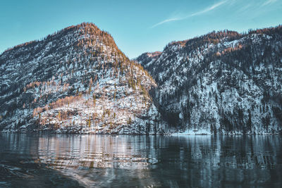 Scenic view of lake by mountains against sky during winter