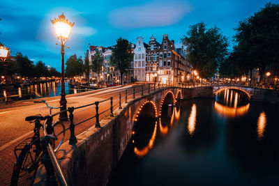 Illuminated bridge over river against sky at night