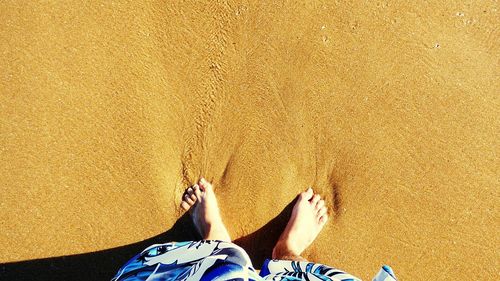 Low section of person standing on sand at beach