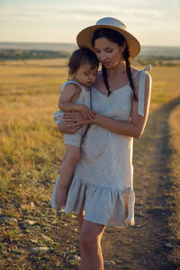 Mother and son goes to the field at sunset in a straw hat