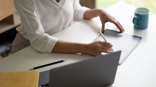 Midsection of woman using digital tablet at office