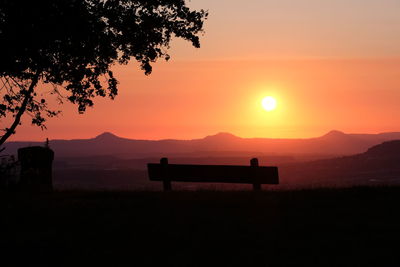 Silhouette bench in park during sunset