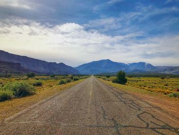 Road leading towards mountains against sky