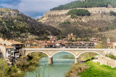 Arch bridge over river amidst buildings in city