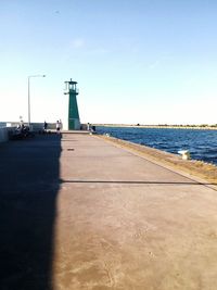 Lighthouse by sea against clear sky