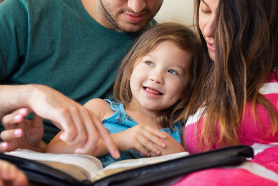 High angle view of parents reading book to daughter