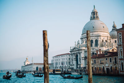 Gondolas in grand canal by san giorgio maggiore church against clear sky