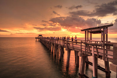 Pier over sea against sky during sunset