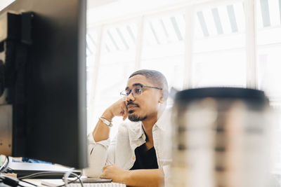 Tired computer programmer looking at computer while working in office