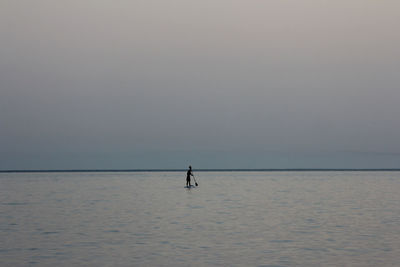 Silhouette person in sea against clear sky