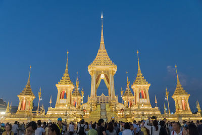 People at temple against clear blue sky