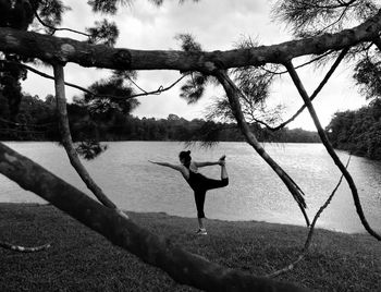 Rear view of woman exercising at lakeshore