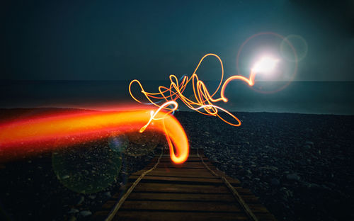 Light paintings on beach against sky at dusk