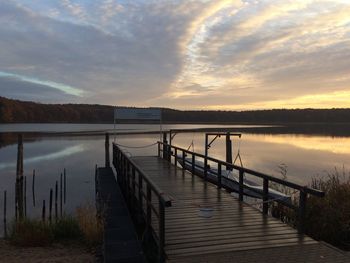 Pier on lake against sky during sunset