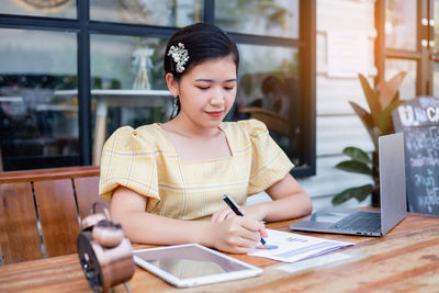 Young woman using phone on table