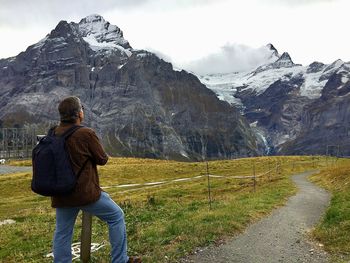 Rear view of man standing on mountain against sky