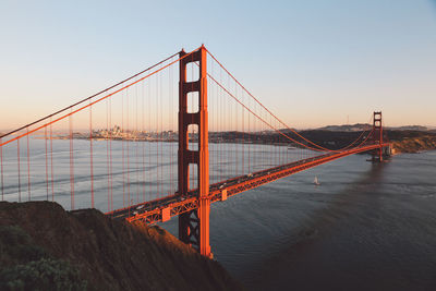 Suspension bridge over river against sky