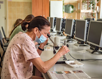 Women examines the preparations under the microscope. classroom activities. practical lesson.