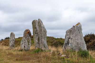 Low angle view of rock formation on field against sky