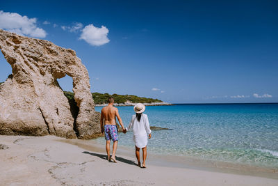 Rear view of women standing at beach against sky