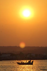 Silhouette boat in sea against orange sky