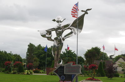 Statue of flags against cloudy sky