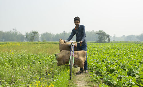 Young farmer carrying vegetable bag on cycle after harvest at farm
