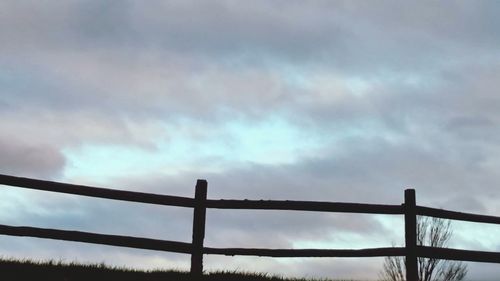 Low angle view of silhouette fence against sky