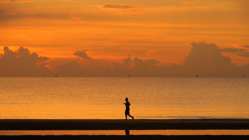 Silhouette man on beach against sky during sunset