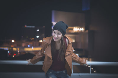 Smiling young woman standing in illuminated city at night