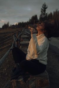 Side view of young woman sitting on railroad track