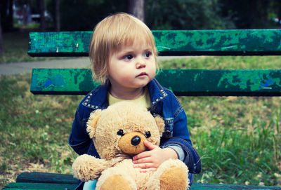 Portrait of cute baby boy sitting on bench