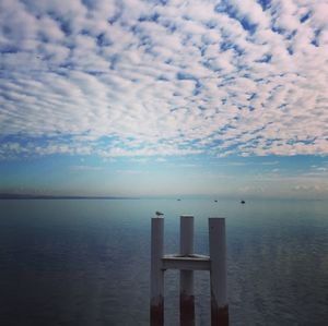 Wooden posts in sea against sky