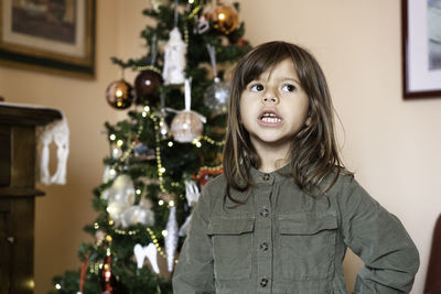 Portrait of girl with christmas tree at home