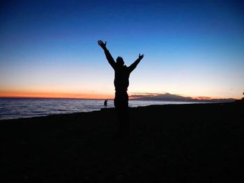 Silhouette of woman standing on beach at sunset