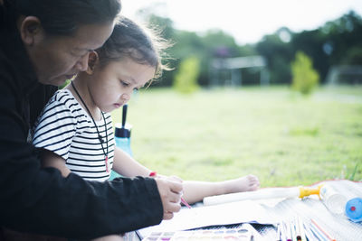 Side view of girl drawing on field