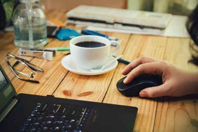 Midsection of person holding coffee cup on table